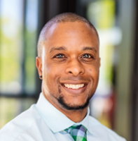 Black man smiling in a dress shirt and tie